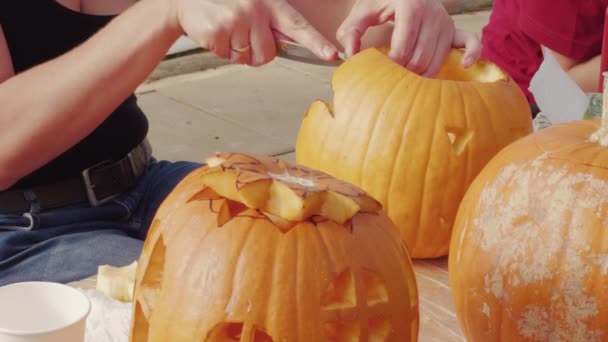 女性の手はお祝いハロウィンのためにオレンジカボチャを彫る テーブルの上に幽霊の家や城を彫刻野菜 いくつかのショット ナイフでカボチャを切る人は ジャック ランタンを作り ワイプで蓋穴を乾燥させます パーティーの装飾の準備 — ストック動画