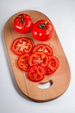 Beyaz arka plan üzerinde izole bir breadboard üzerinde bütün ve dilimlenmiş taze domates