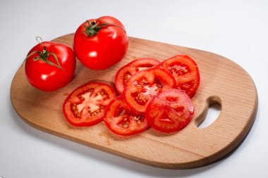 Beyaz arka plan üzerinde izole bir breadboard üzerinde bütün ve dilimlenmiş taze domates