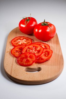 Beyaz arka plan üzerinde izole bir breadboard üzerinde bütün ve dilimlenmiş taze domates