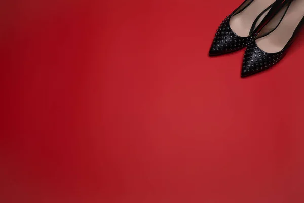 A pair of black pumps shoes with spikes isolated on red background