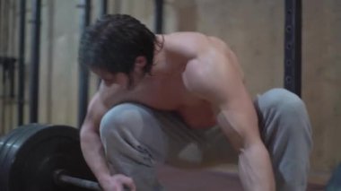 Genç bir adam, güzel vücut şakaları yapan bir sporcu ve yaya geçidinde, ağır bir halterle oynuyor.