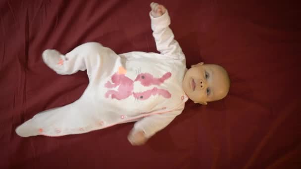 Baby ligt op zijn rug en glimlacht, huwt, is verrast — Stockvideo