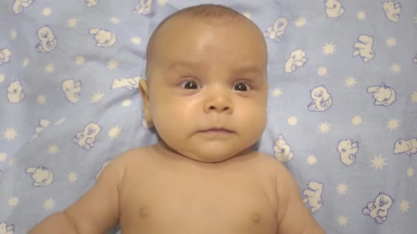 아기는 그의 등에 누워 미소, 울고, 놀란다 — 비디오