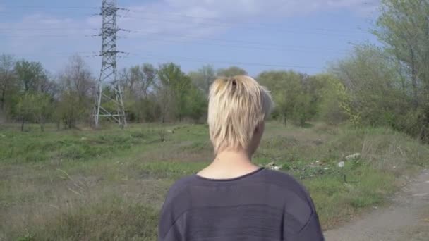 Evsiz bir kadın kırsal bir yolda yürüyor, bir sürü çöpü etrafa saçıyor. — Stok video