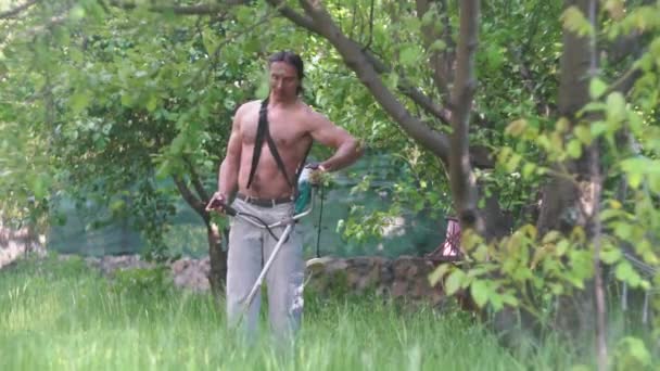 Handsome man with muscular muscles, naked torso, mowing grass — Stock Video