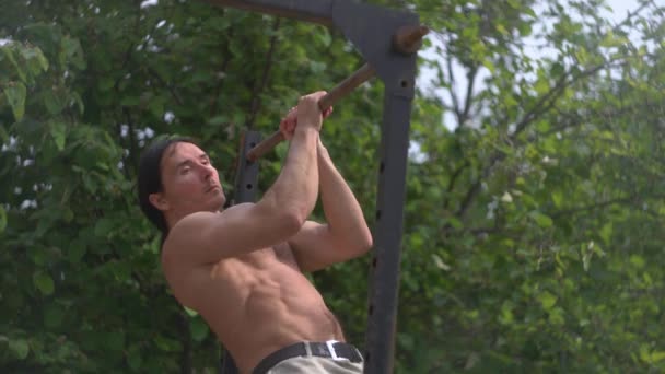 Entrenamiento en la barra horizontal, un hombre haciendo pull-ups, entrenamiento al aire libre — Vídeos de Stock