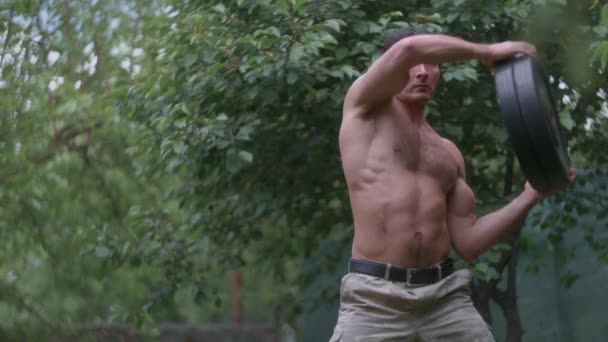 Muskelprotz beim Training mit einer Hantelscheibe. Fitness-Mann trainiert an der Rumpfmuskulatur — Stockvideo