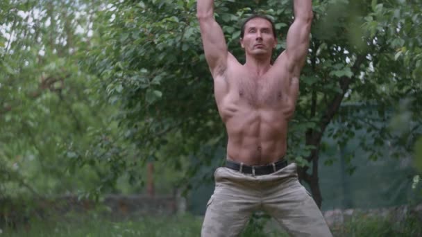 Fitness człowiek kulturysta trening za pomocą sztangi i ciężarów, podnoszenie ciężarów ćwiczenia mięśni sportowiec moc podnoszenie ciężarów robi przysiady w ogrodzie — Wideo stockowe