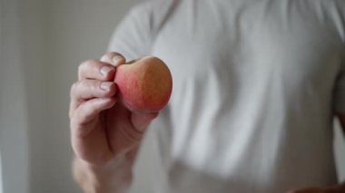 A person is holding a perfectly ripe and delicious peach, capturing the true essence of healthy snacking. Slow motion. High quality 4k footage