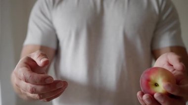 A man is holding a perfectly ripe and delicious peach, capturing the true essence of healthy snacking. Slow motion. High quality 4k footage