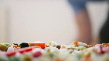 Yetenekli bir zanaatkar şef çeşitli taze sebzelerle süslenmiş canlı bir pizzayı ustalıkla bir araya getirir.