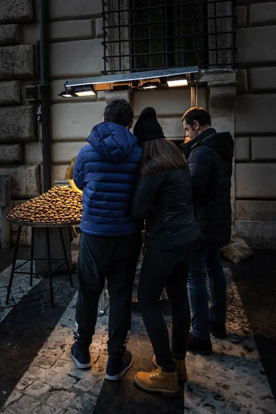 kestane satıcısı ve genç çift kışın sokakta yürüyen, kavrulmuş kestane satın.