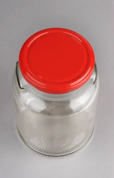 灰色の背景に分離された赤いカバー付きの空のガラス瓶 — ストック写真