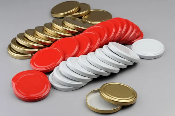 Verschiedene Schraubverschlüsse für Glasgefäße. für Konserven, Konserven. weiß, rot, goldene Kappen auf grauem Hintergrund — Stockfoto