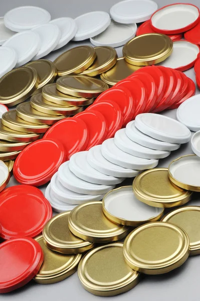 Verschiedene Schraubverschlüsse für Glasgefäße. für Konserven, Konserven. weiß, rot, goldene Kappen auf grauem Hintergrund — Stockfoto