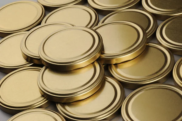Screw caps for glass jars. For canning, canned food. Golden caps on gray background — Stock Photo, Image