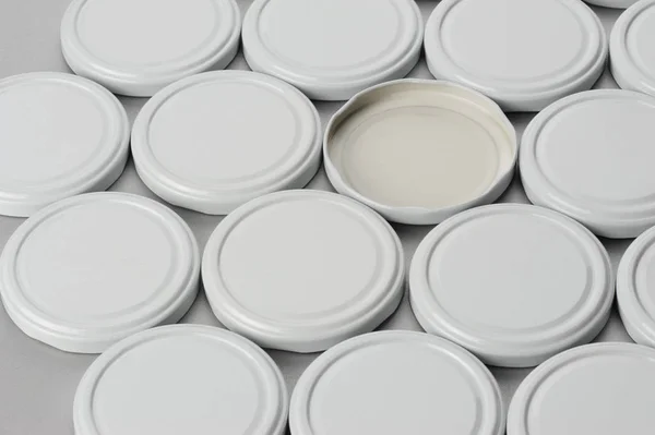 Csavaros kupakok üvegedények. Konzervezés, konzerv élelmiszer. Fehér sapkák szürke háttérrel — Stock Fotó
