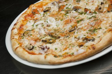 Siyah bir arka plan üzerinde peynir, mantar ve deniz ürünleri ile lezzetli pizza