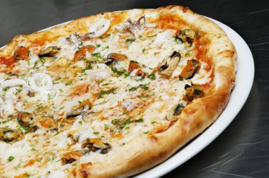 Siyah bir arka plan üzerinde peynir, mantar ve deniz ürünleri ile lezzetli pizza