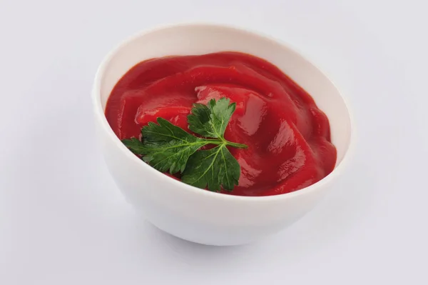 Pequeño un tazón de salsa de tomate rojo ketchup y perejil aislado sobre fondo blanco — Foto de Stock