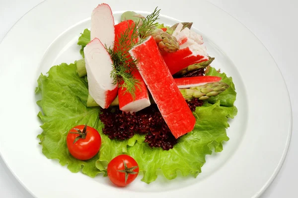 Caranguejo paus em um prato com salada no fundo branco — Fotografia de Stock