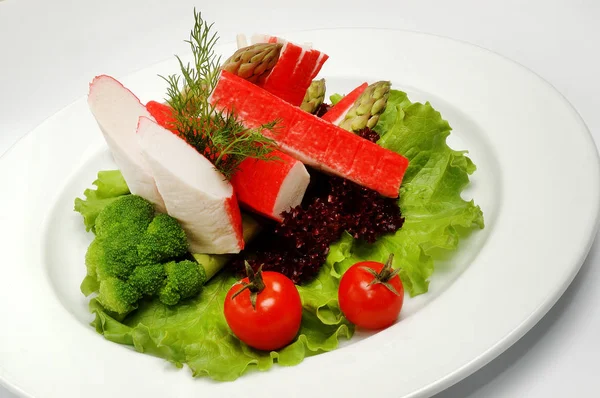 Caranguejo paus em um prato com salada no fundo branco — Fotografia de Stock