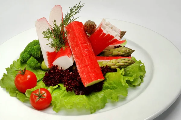 Rák botok egy tányérra salátával, fehér alapon — Stock Fotó