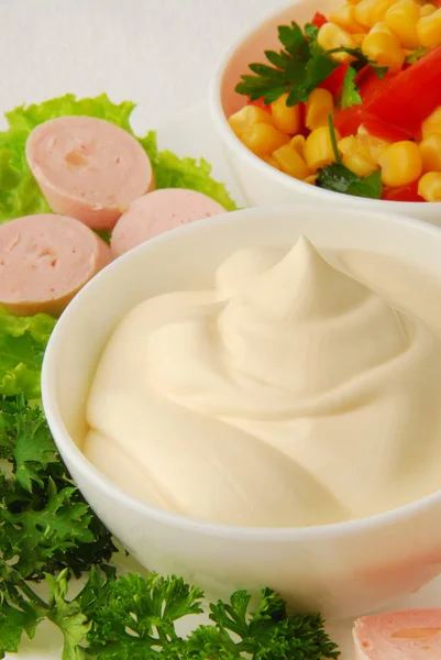 Ceramic dip bowl full of mayonnaise, sausages, parsley, isolated on white background