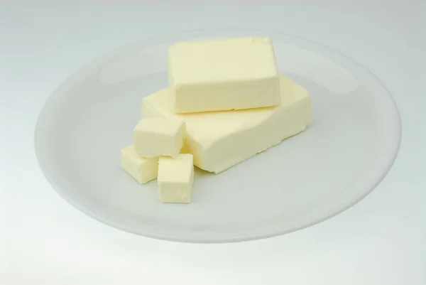 Kawałek świeżego masła organicznego na płycie izolowanej na szarym tle w zbliżenie — Zdjęcie stockowe