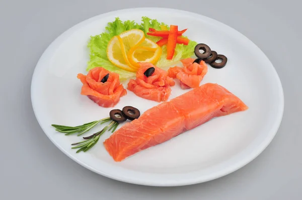 Filets de roses décoratives au saumon frais, avec citron, olives dans l'assiette. Isolé sur un fond gris — Photo