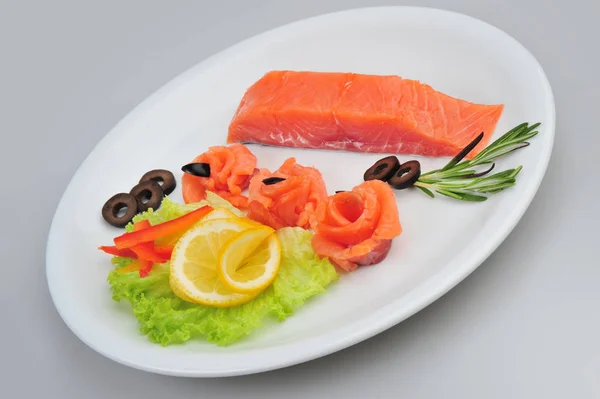 Filetes de rosas decorativas de salmão fresco, com limão, azeitonas no prato. Isolado em um fundo cinza — Fotografia de Stock