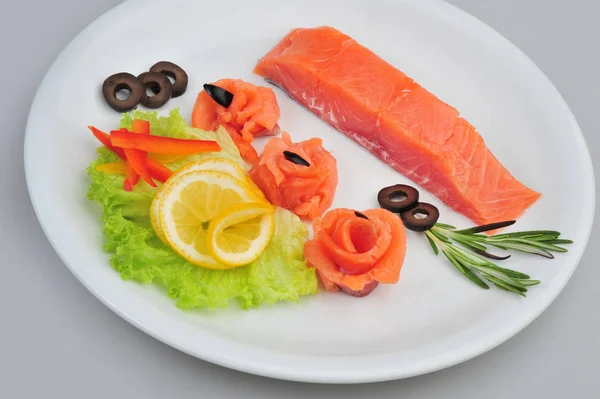 Filets de roses décoratives au saumon frais, avec citron, olives dans l'assiette. Isolé sur un fond gris — Photo