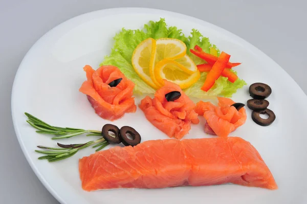 新鲜的鲑鱼装饰玫瑰片，盘子上有柠檬、橄榄。在灰色背景上隔离 — 图库照片