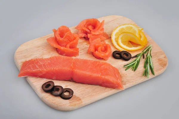 Filetes de rosas decorativas de salmão fresco, com limão, azeitonas no tabuleiro. Isolado em um fundo cinza — Fotografia de Stock