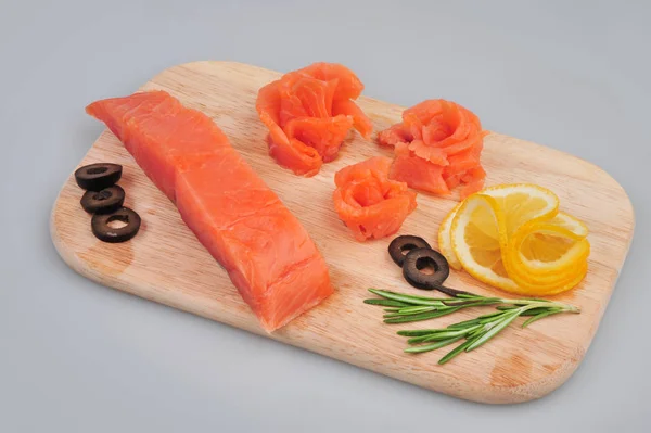 Filetes de rosas decorativas de salmão fresco, com limão, azeitonas no tabuleiro. Isolado em um fundo cinza — Fotografia de Stock