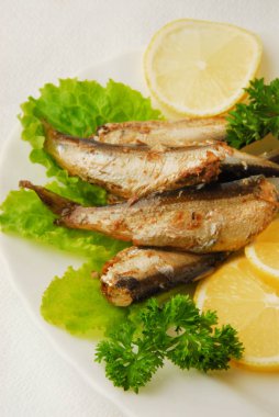 Tavada baharatlı sprats limon, salata bir tabakta