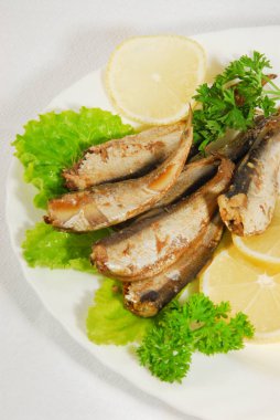 Tavada baharatlı sprats limon, salata bir tabakta