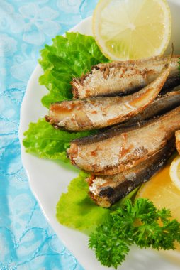 Tavada baharatlı sprats limon, salata bir tabakta