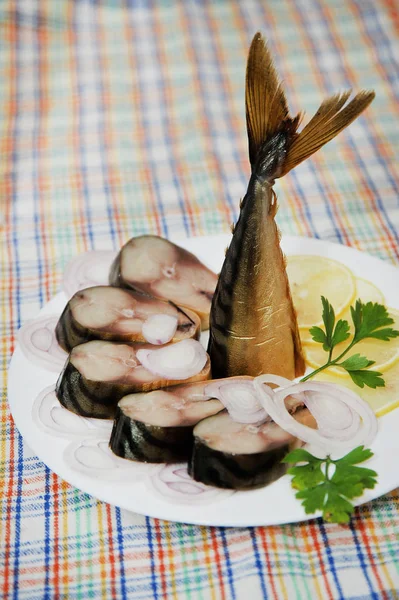 Caballa ahumada caliente en un plato con limón y perejil sobre la mesa — Foto de Stock