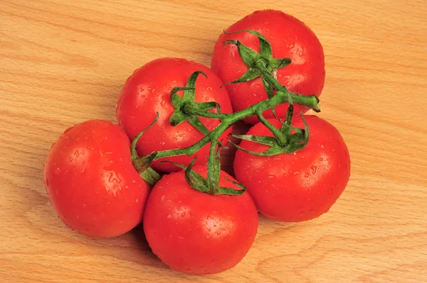 Tomates rouges entières de groupe avec branche verte isolée sur fond en bois. sain biologique vitamine plante tomate gros plan photo — Photo