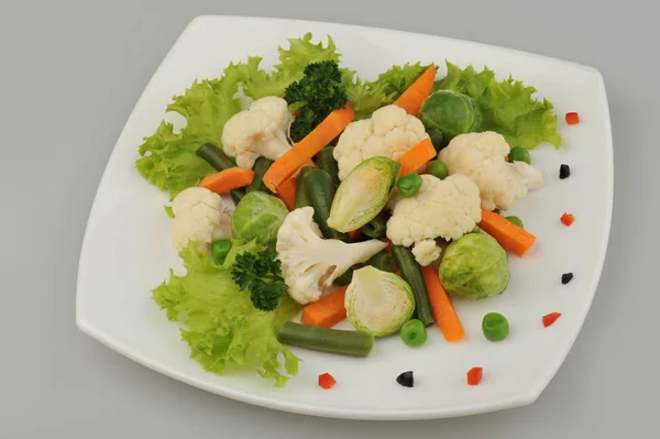 Diverse verdure verdi sul piatto sfondo grigio — Foto Stock