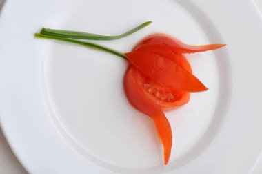 Beyaz tabak çiçek kesilmiş domates süslenmiş