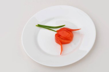Beyaz tabak çiçek kesilmiş domates süslenmiş