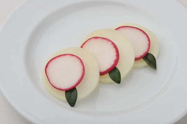 Sliced radishes, onions with bay leaves on a plate