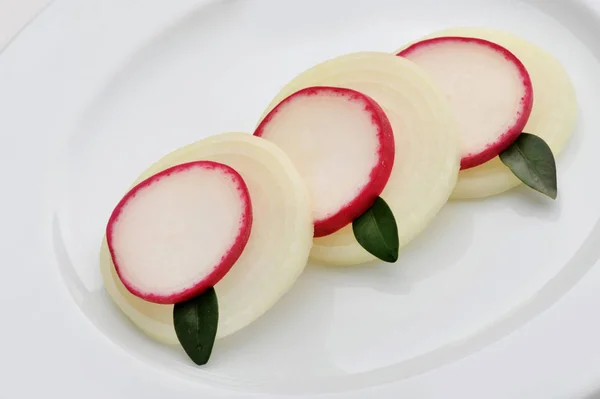 Sliced radishes, onions with bay leaves on a plate