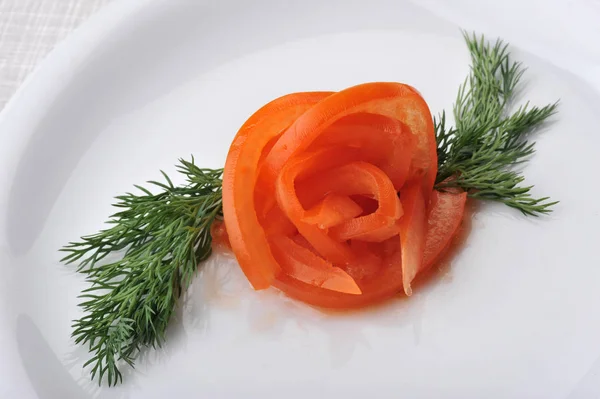 Прикрашений на білій тарілці розрізаний помідор і кріп — стокове фото