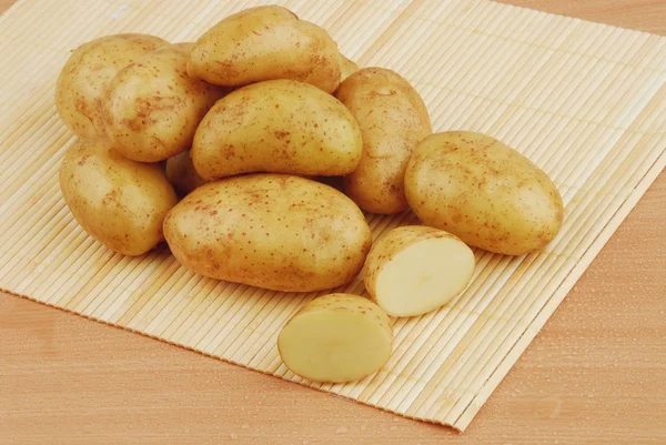 Viele rohe Kartoffeln auf Bambus stehen auf grauem isolierten Hintergrund — Stockfoto