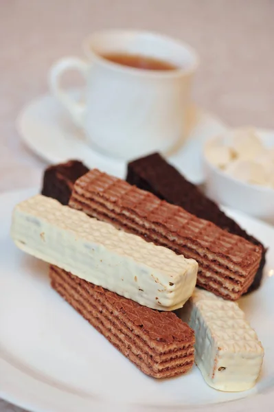 Bir fincan sıcak çay ve beyaz yüzeyde farklı dolgular ile klasik Rus waffle bir avuç. Sabah ziyafetinin natürmortu, çay için konsept tatlılar