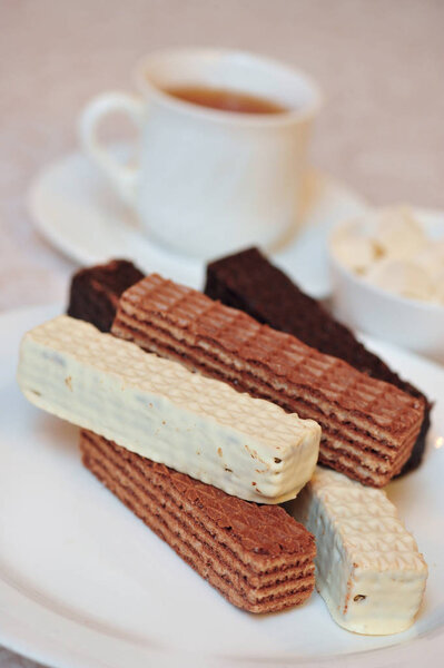 A cup of hot tea and a handful of classic Russian waffles with different fillings on a white surface. Still-life of morning feast, concept sweets for tea
